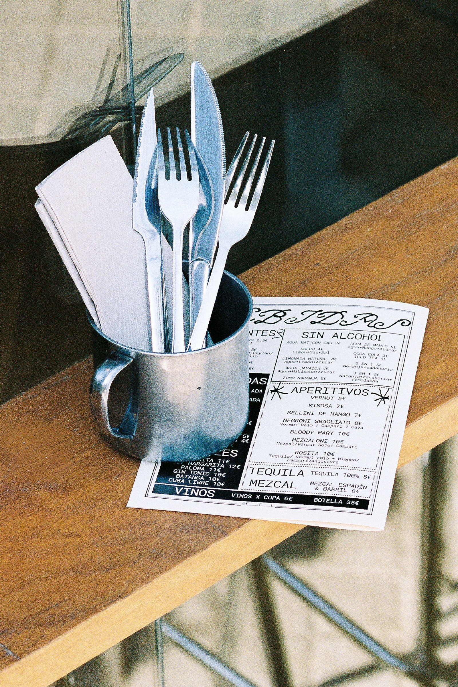 Cubiertos plateados sobre una servilleta blanca, junto a una carta impresa de ETL con apartados de aperitivos, tequila, mezcal y vinos.
